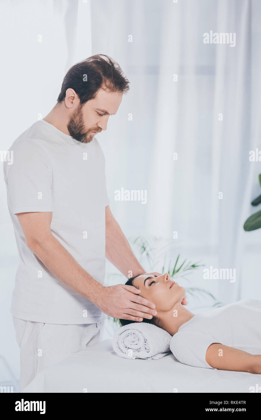 Junge Frau mit geschlossenen Augen, die Reiki - Behandlung von bärtigen Heiler Stockfoto