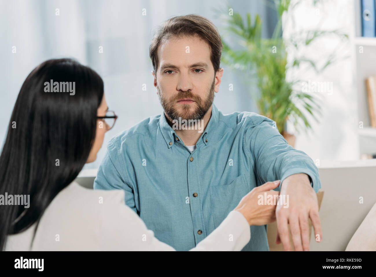 Junge Frau in Brillen die Hand des bärtigen Mann während der Hypnotherapie Stockfoto