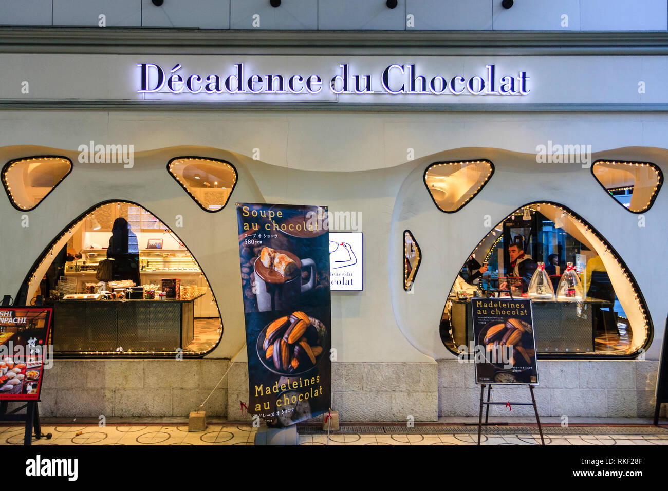 Tokyo, Ginza. Dekadenz du Chocolat, Spezialität Schokolade Shop. Menü boards außerhalb zwei große und mehrere kleine beleuchtete Fenster, Menschen im Inneren. Stockfoto