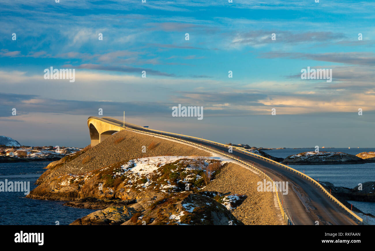 Atlantic Ocean Road - Atlanterhavsvegen im Winter sonniger Tag. Berühmte hohe Brücke über das Meer genannt Storseisundbrua und schöne verschneite Berge in einer Stockfoto