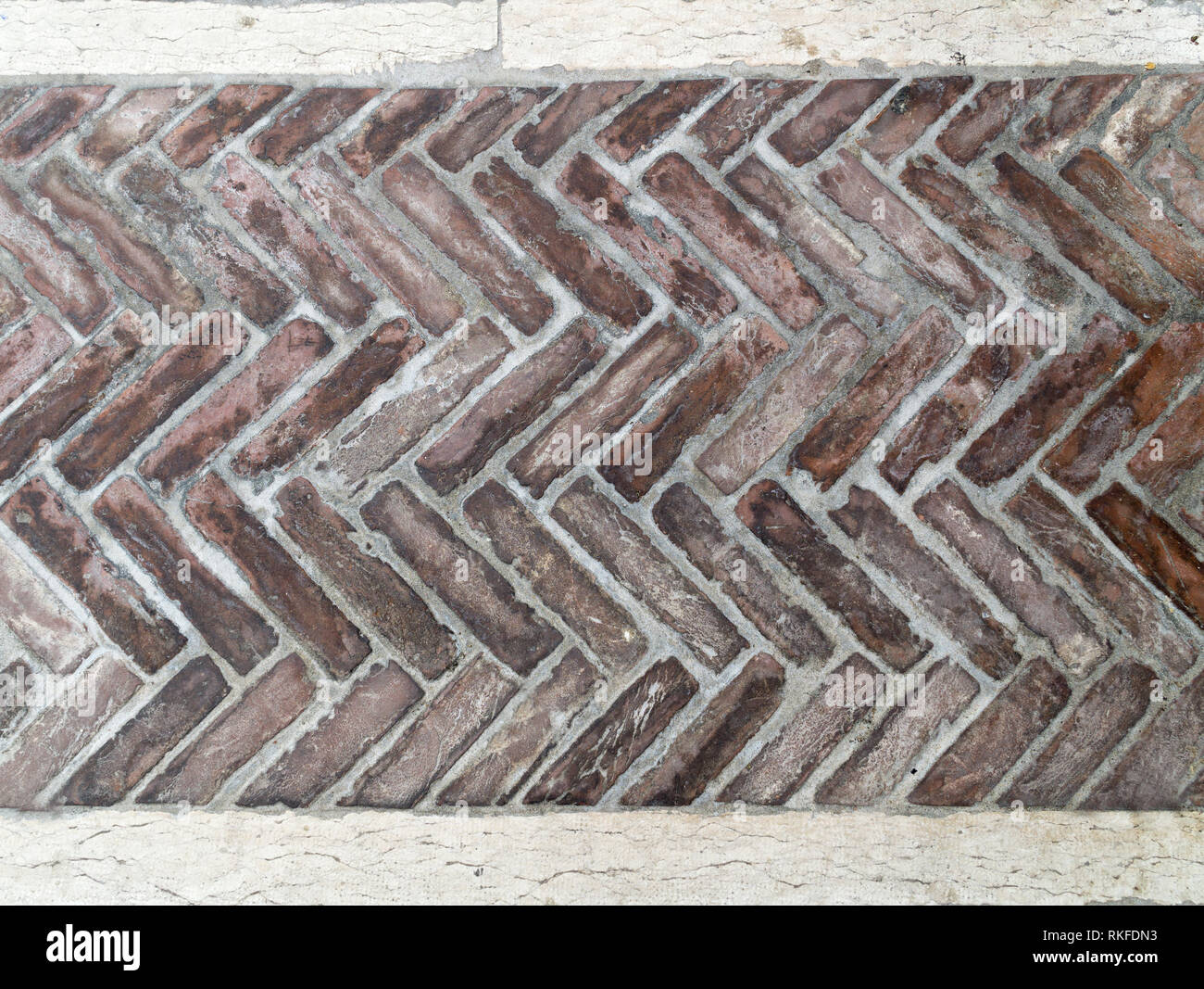 Alten Ziegel Pflaster in einem herringbone Style für Hintergrund, alte braune Ziegel Fliesen mit Zickzack Muster. Stockfoto