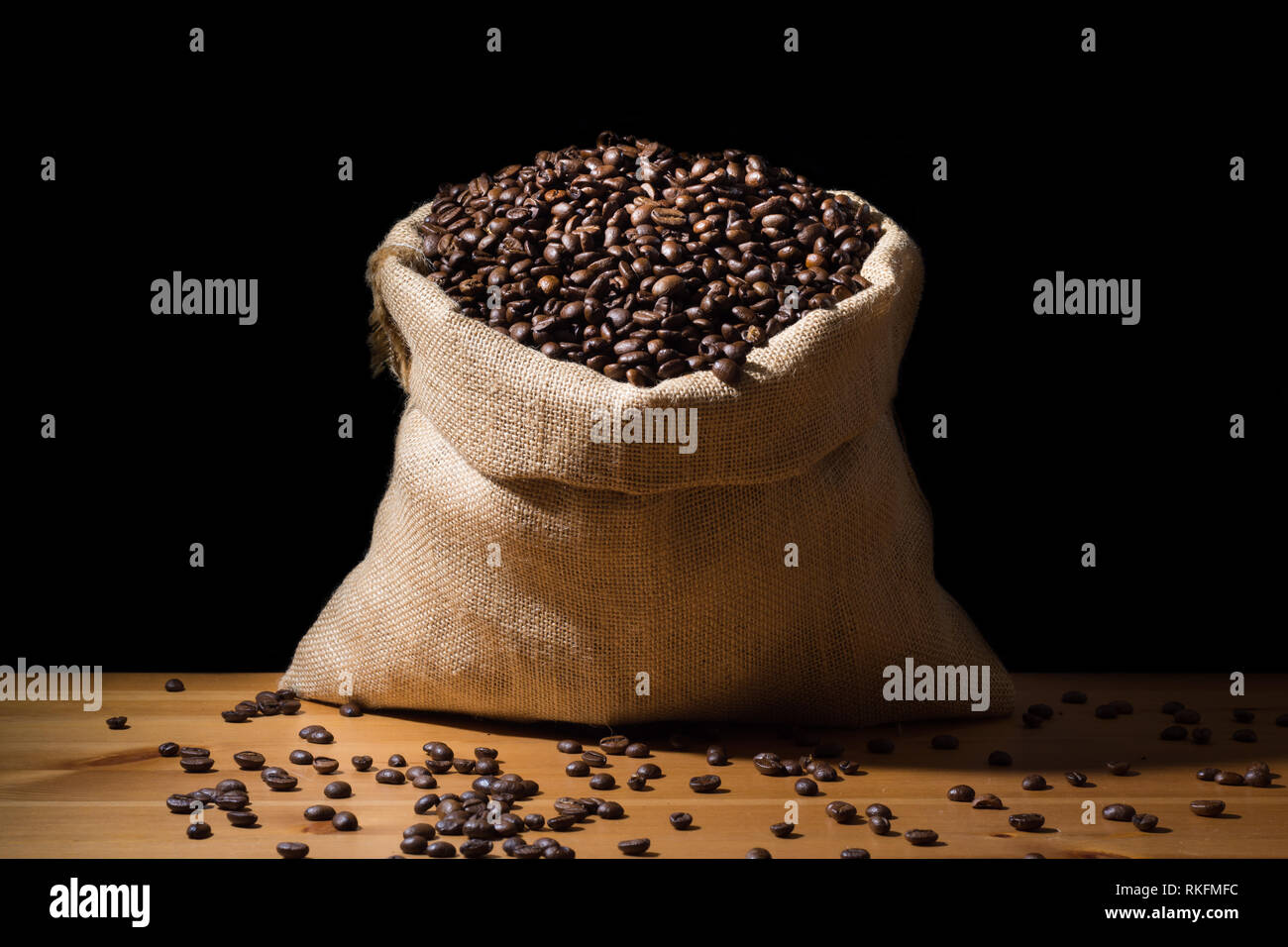 Close up geröstete Kaffeebohnen in einem sackleinen hessische Sack und isoliert in Schwarz. Stockfoto