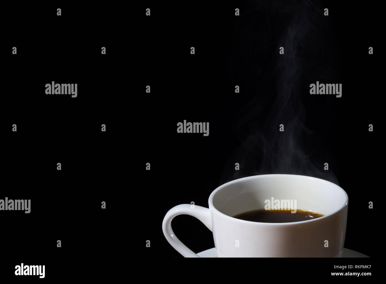 Weiße Tasse Kaffee mit Dampf oder Dunst und in Schwarz isoliert. Stockfoto