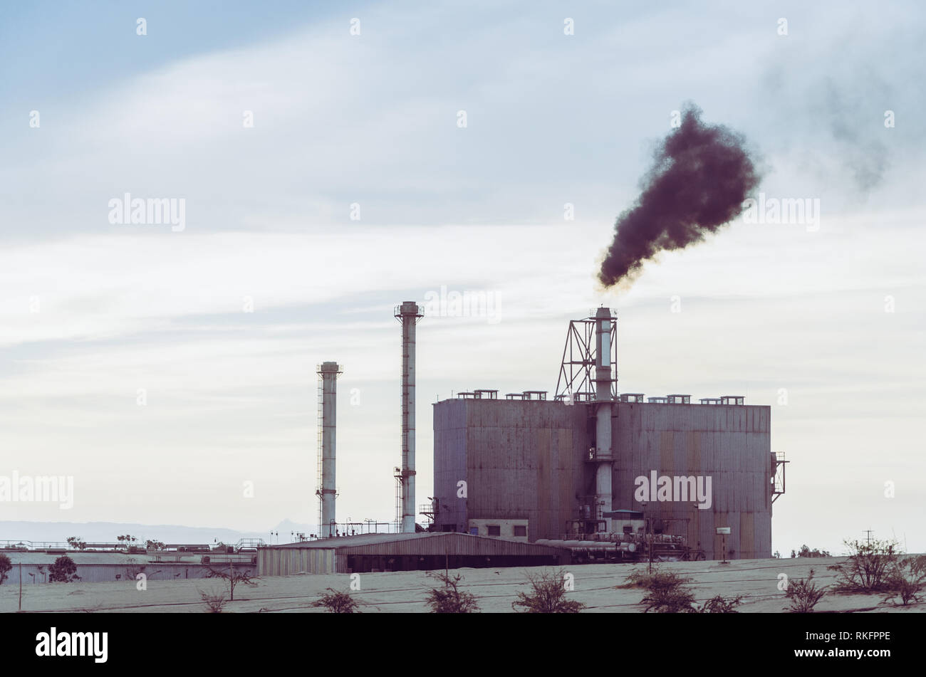 Eine Fabrik weht der Rauch in den Himmel während des Morgens. Stockfoto