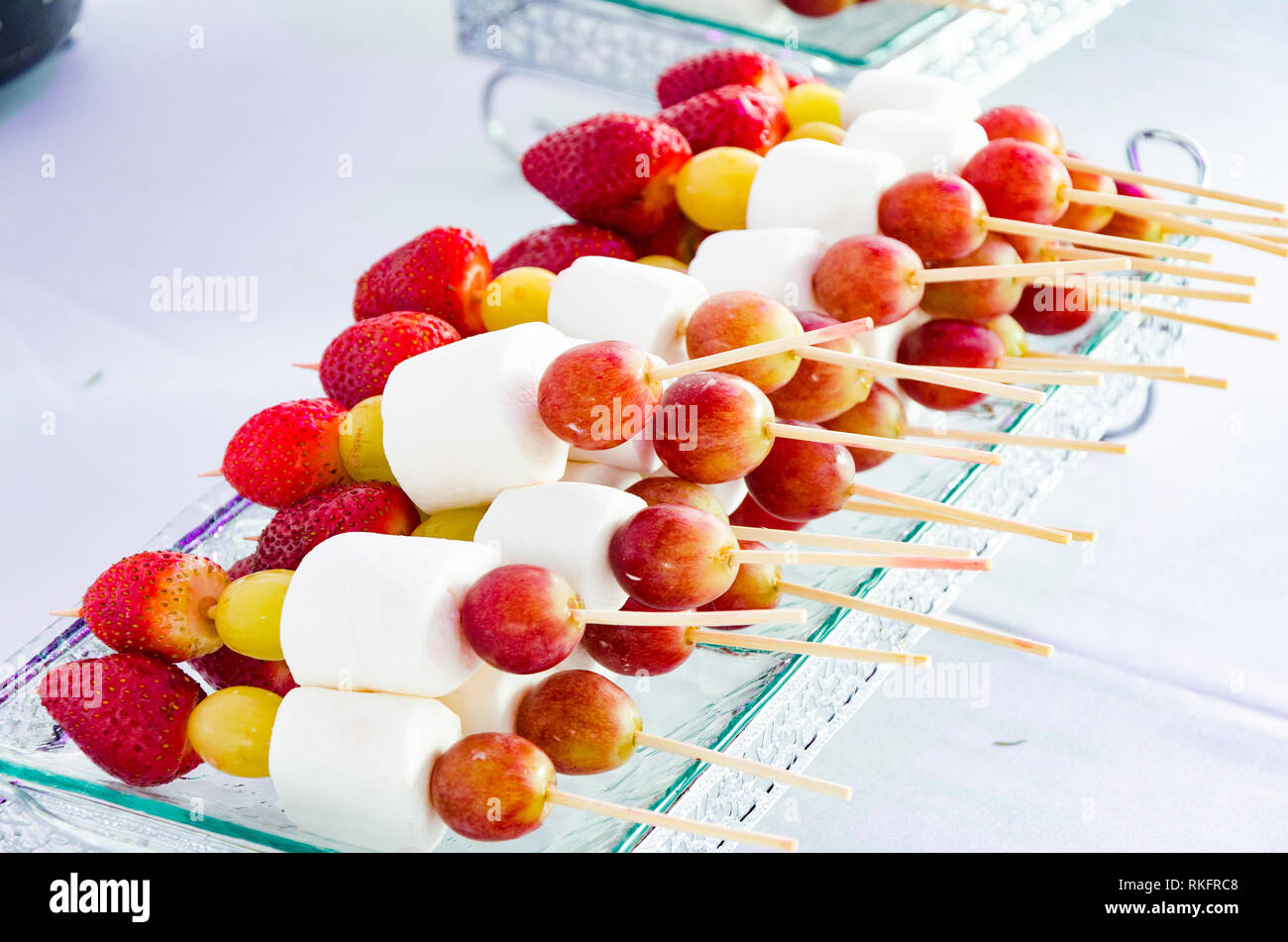 Spieße mit Erdbeeren, Marshmallows und Trauben in einem Brunnen serviert, Konzept der Party Dekoration oder Veranstaltungen. Stockfoto