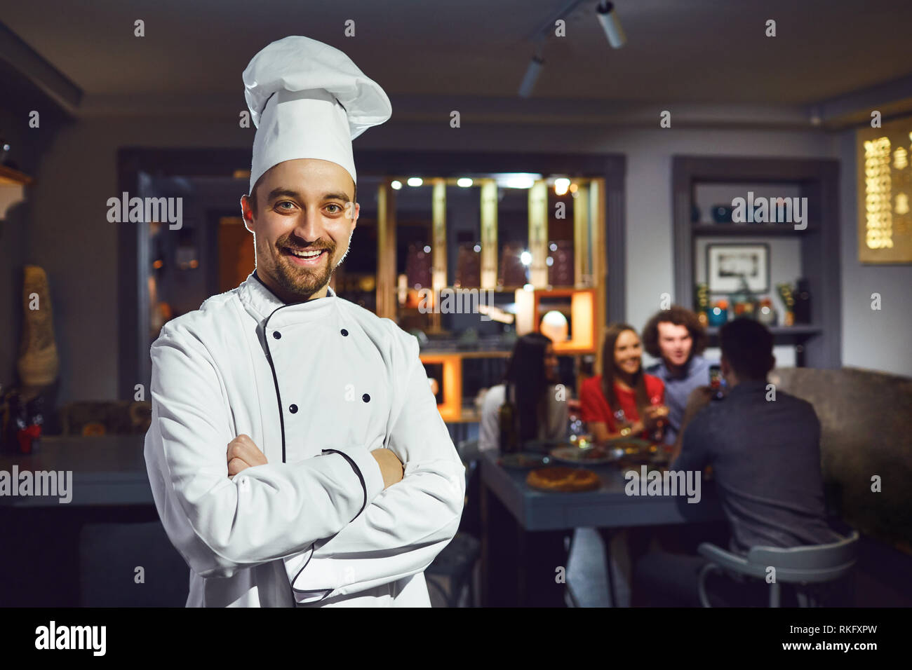 Ein männlicher Cook ist lächelnd vor dem Hintergrund der ein Restaurant. Stockfoto