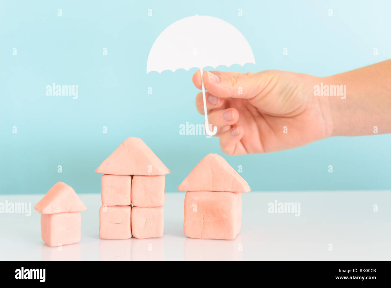 Hand einen Regenschirm über ein Haus, das Konzept der Sicherheit und Versicherung von Immobilien Stockfoto
