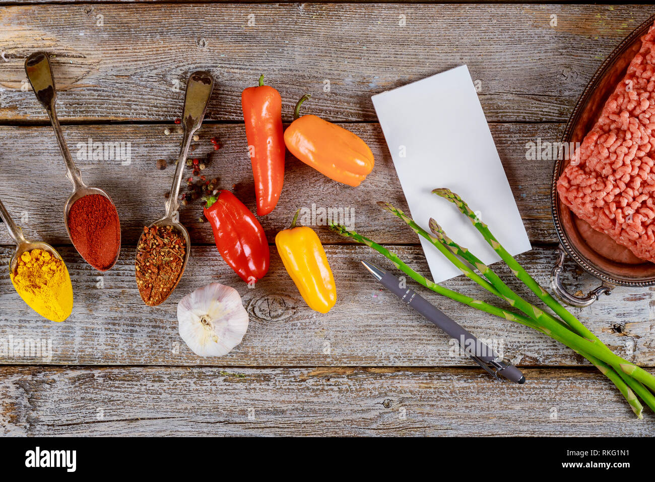 Bunte Paprika Füllung Zubereitung mit Zutaten zum Kochen: Fleisch, frische grüne Würze und Bügeleisen Topf auf rustikalen Tisch Hintergrund Stockfoto