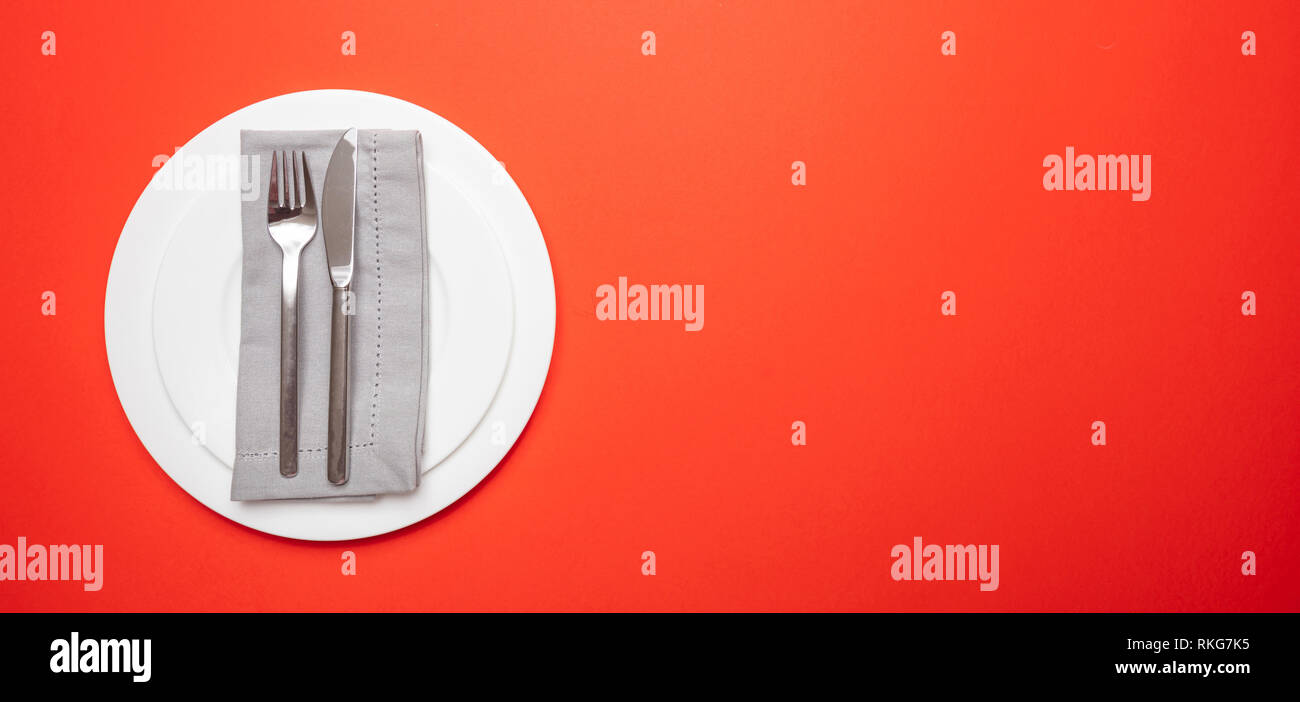 Tabelle setzen, Einstellung auf Rot. Satz von leeren weißen Teller und Besteck auf rot, orange Farbe Hintergrund, Banner, Anzeigen, Kopieren Raum Stockfoto