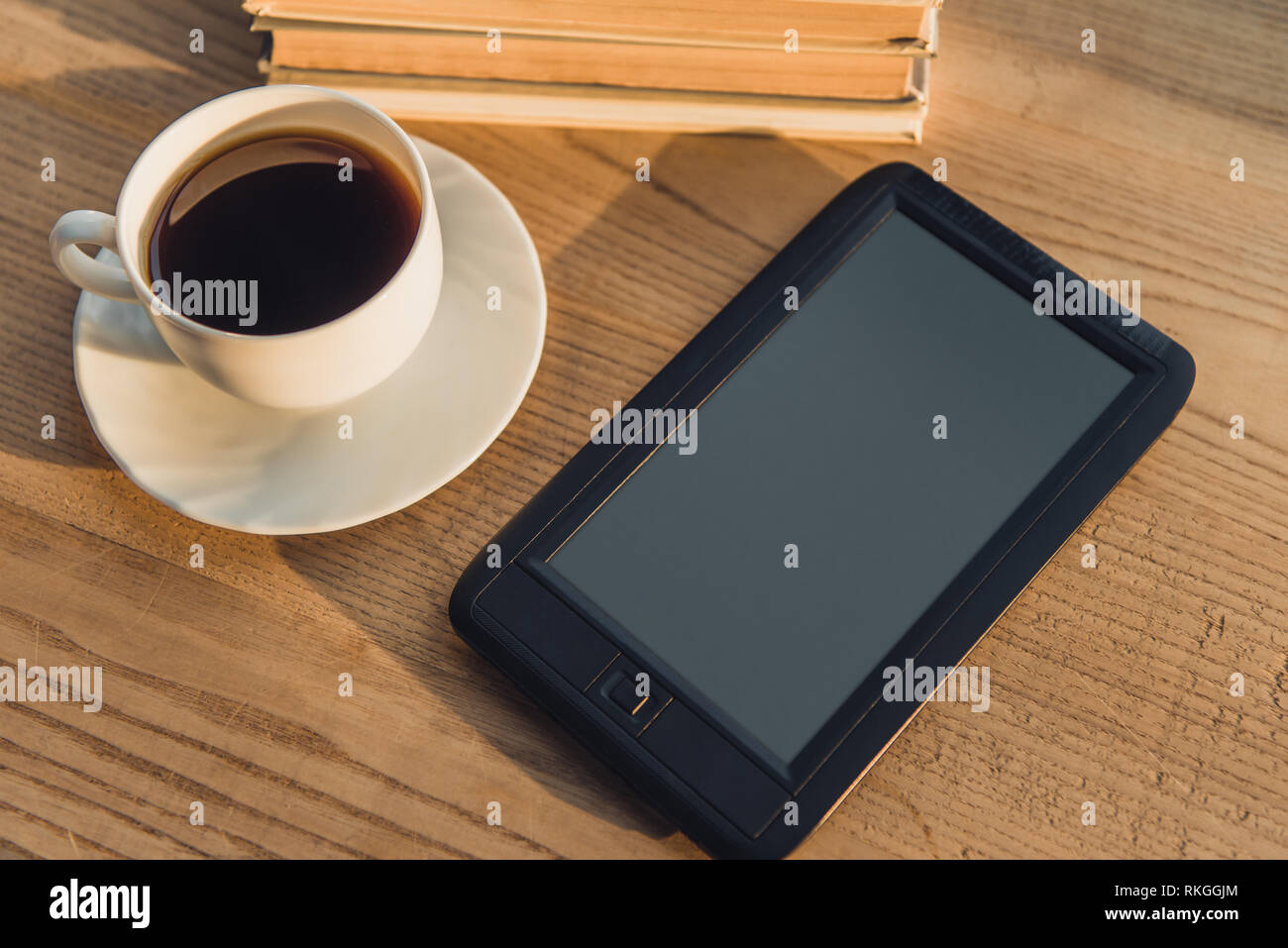 Schwarz e-Reader mit leerer Bildschirm liegen in der Nähe der Schale mit Kaffee auf Tisch Stockfoto