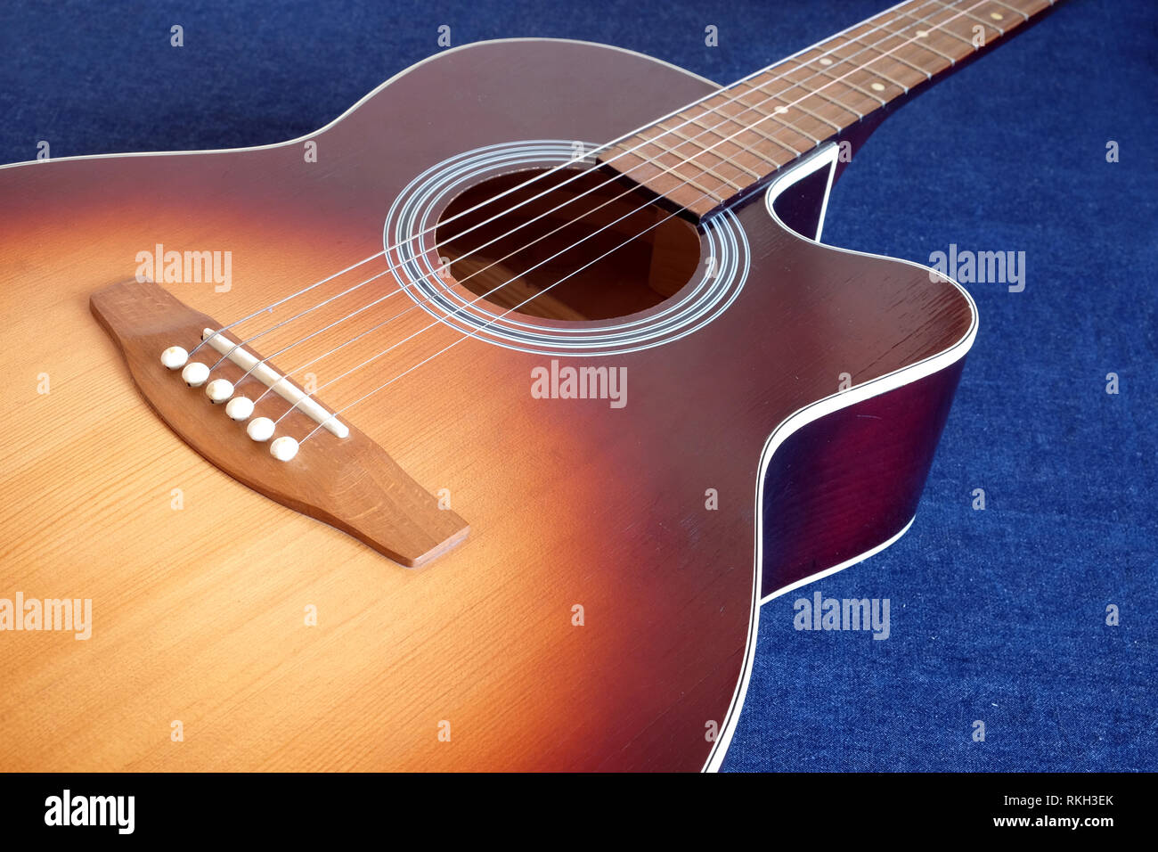 Klassische akustische sechs Saiten sunburst Farbe Top von mit Cutaway Fragment auf Jeans Hintergrund Seitenansicht closeup Fichte Gitarre Stockfoto