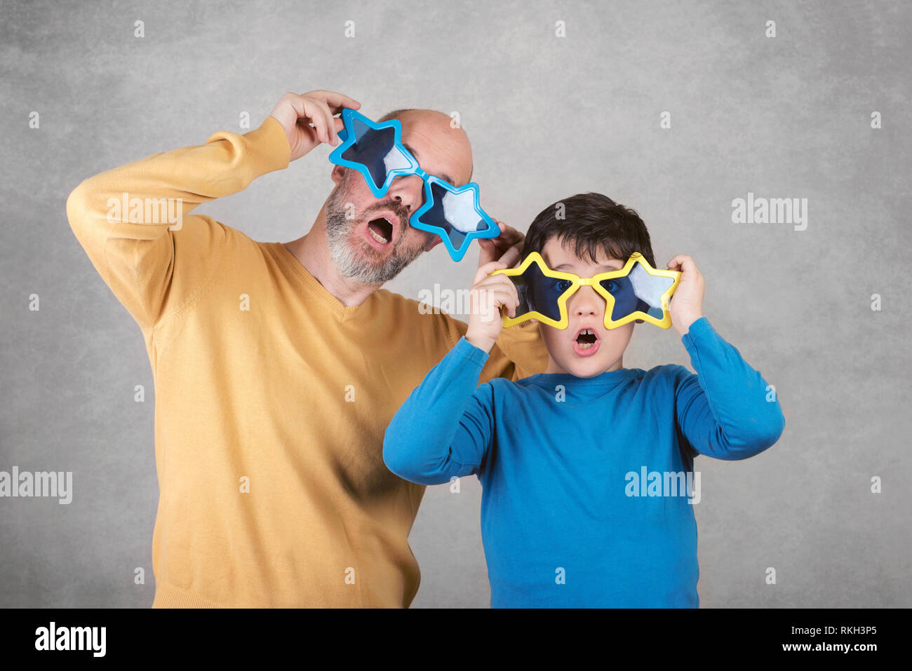 Vatertag, Vater und Sohn mit lustigen Sonnenbrille auf grauem Hintergrund Stockfoto