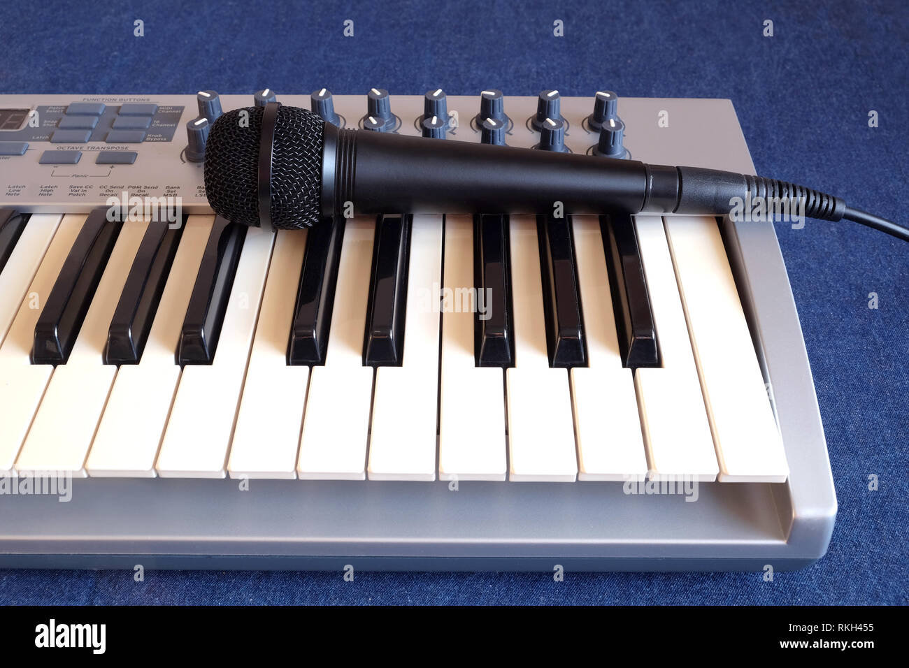Schwarz Mikrofon auf elektronische Synthesizer Keyboard mit vielen Drehknöpfe denim Hintergrund Vorderansicht closeup Stockfoto