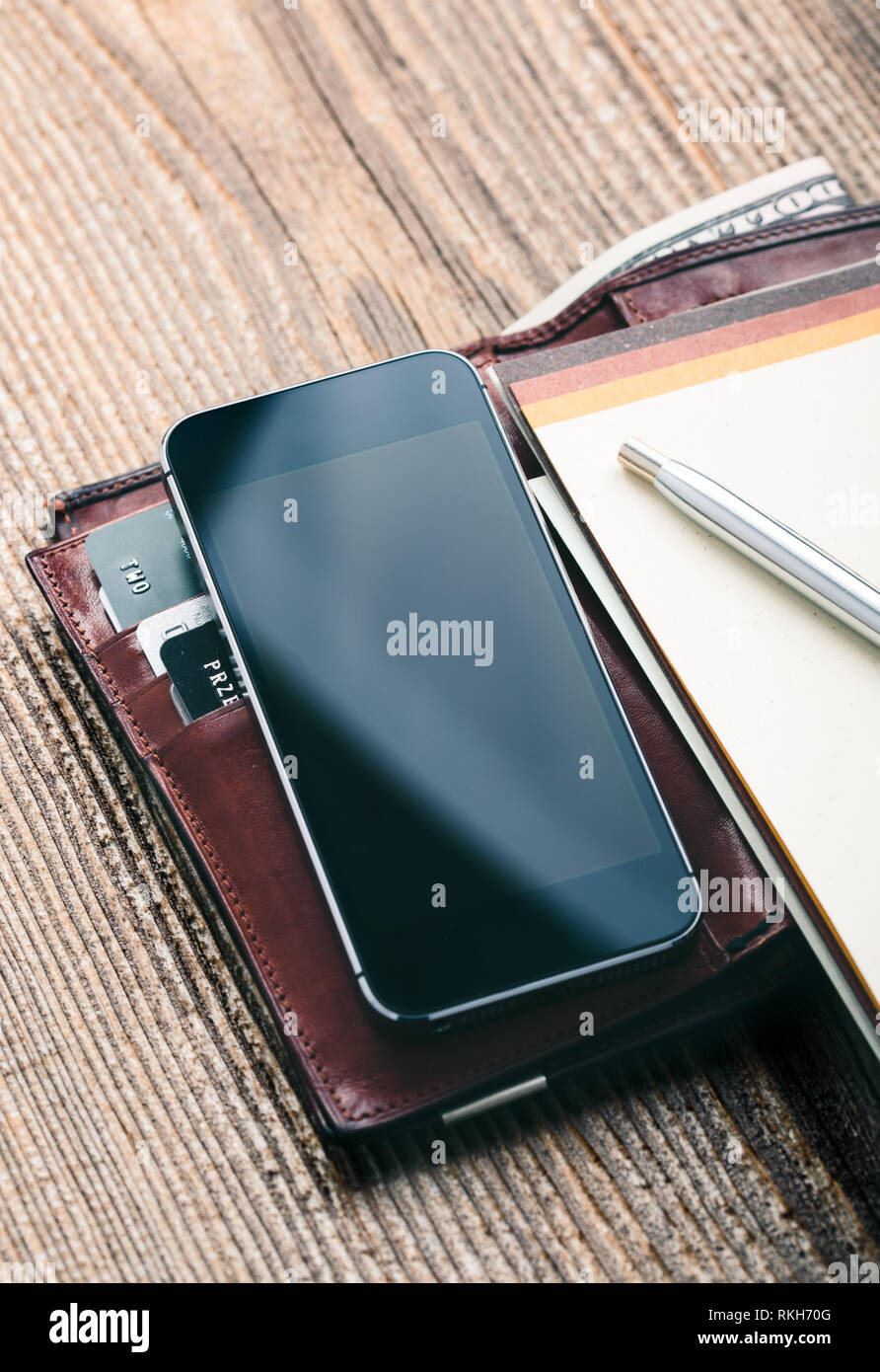 Mit leerer Bildschirm, Portemonnaie, Dollar, Banknoten, Smartphone, Debit Kreditkarten und Notebook auf hölzernen Tisch. Blick von oben. Hochformat Stockfoto