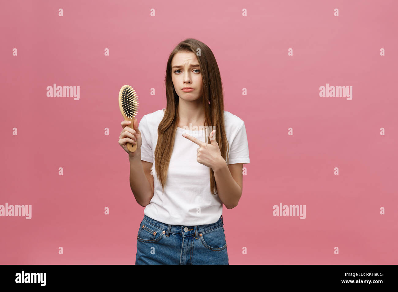 Mädchen auf einem rosa Hintergrund mit einem Kamm für die Haare, das Haar problem Stockfoto