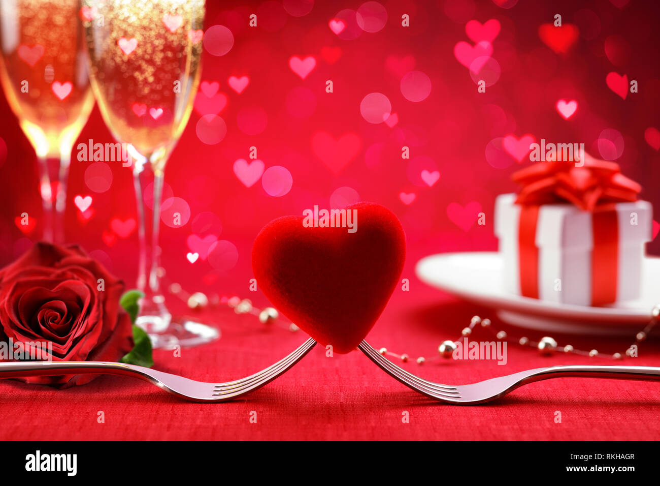 Romantisches Abendessen - Gabeln und Herz mit Defokussierten Geschenk und Champagner - Valentinstag Hintergrund Stockfoto