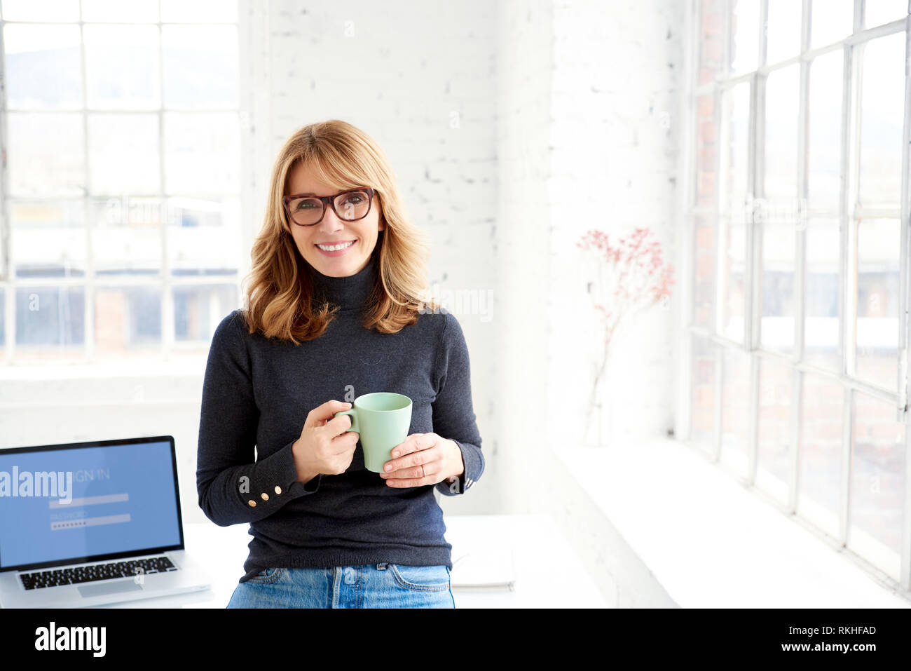 Portraitfotos von attraktiven casual Geschäftsfrau holding Becher in der Hand, während man im Büro Schreibtisch und entspannend. Stockfoto