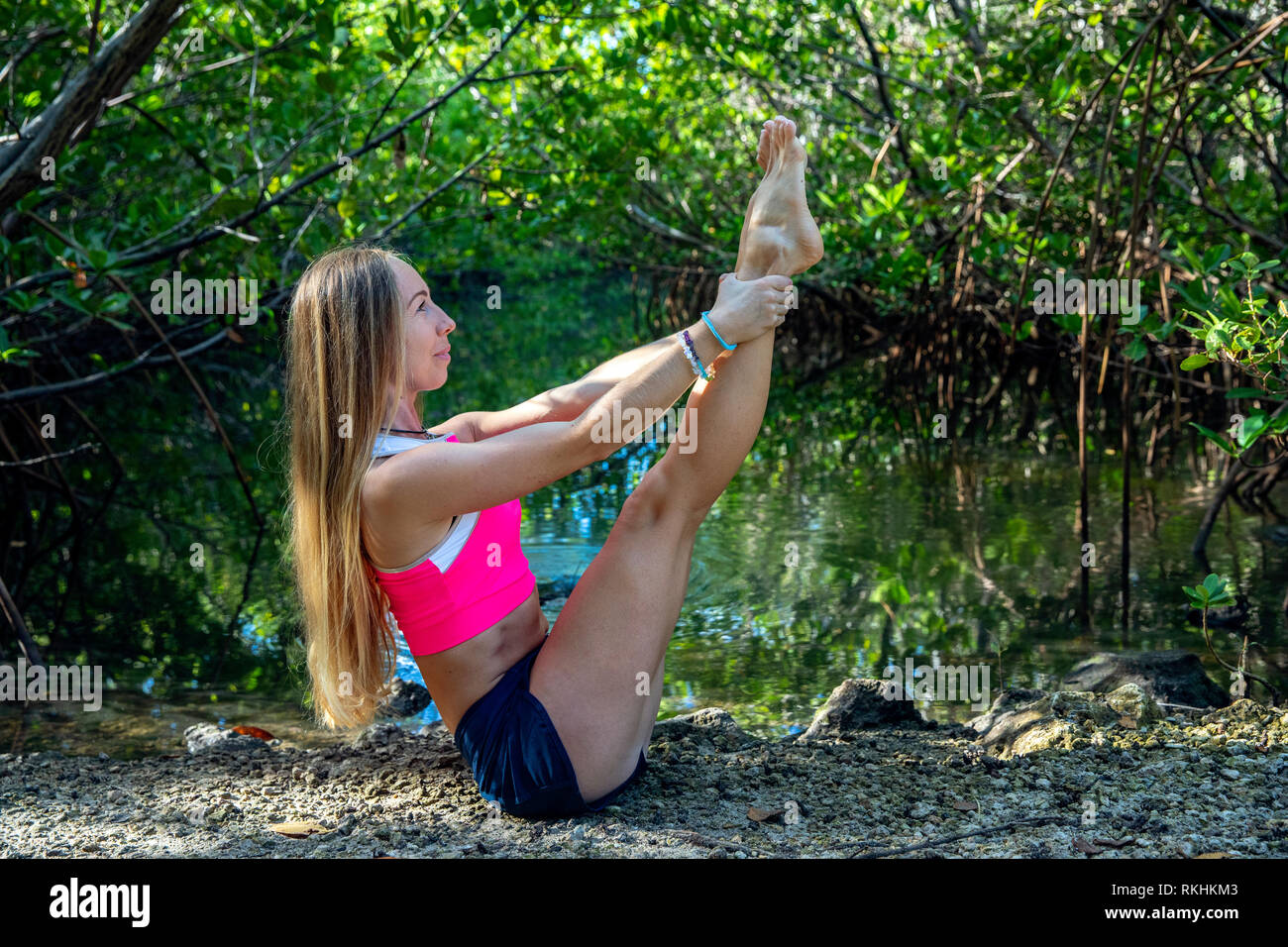 Junge Frau mit Yoga (modifizierte Boot Pose-Navasana) in einer natürlichen Umgebung - Fort Lauderdale, Florida, USA Stockfoto