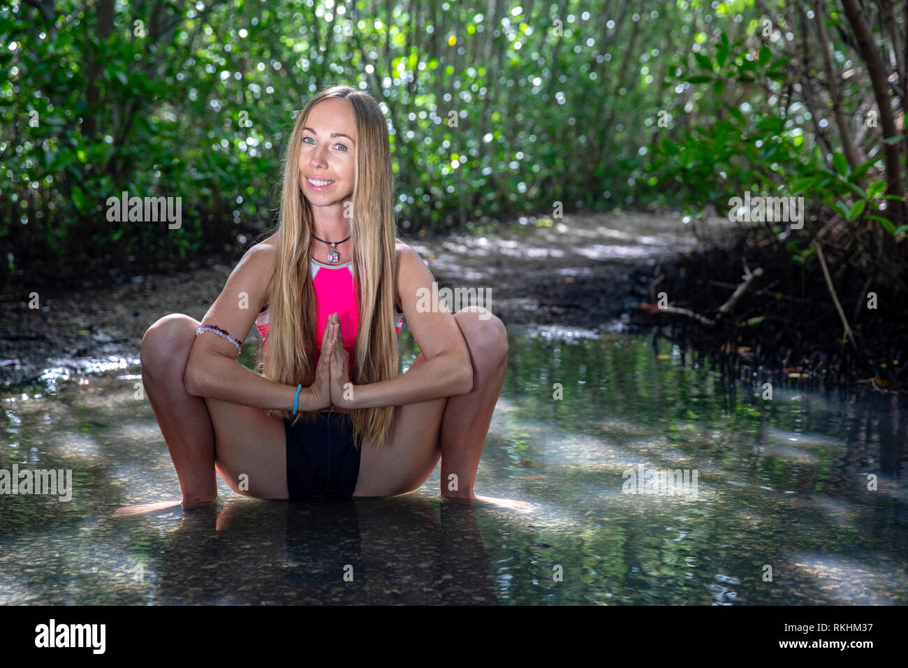 Junge Frau mit Yoga (Garland Pose-malasana) in einer natürlichen Umgebung - Fort Lauderdale, Florida, USA Stockfoto