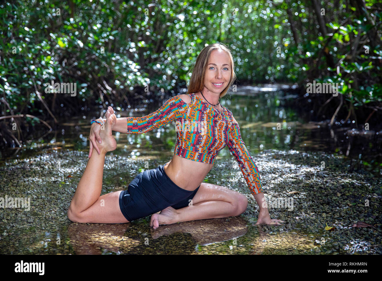 Junge Frau mit Yoga (One-Legged König Taube - Eka Pada Rajakapotasana) in einer natürlichen Umgebung - Fort Lauderdale, Florida, USA Stockfoto