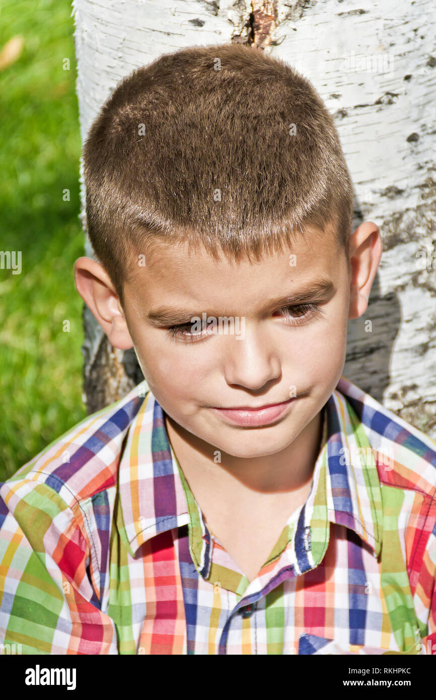 Süße brünette Junge elf Jahre alt im Baum Hintergrund Stockfoto