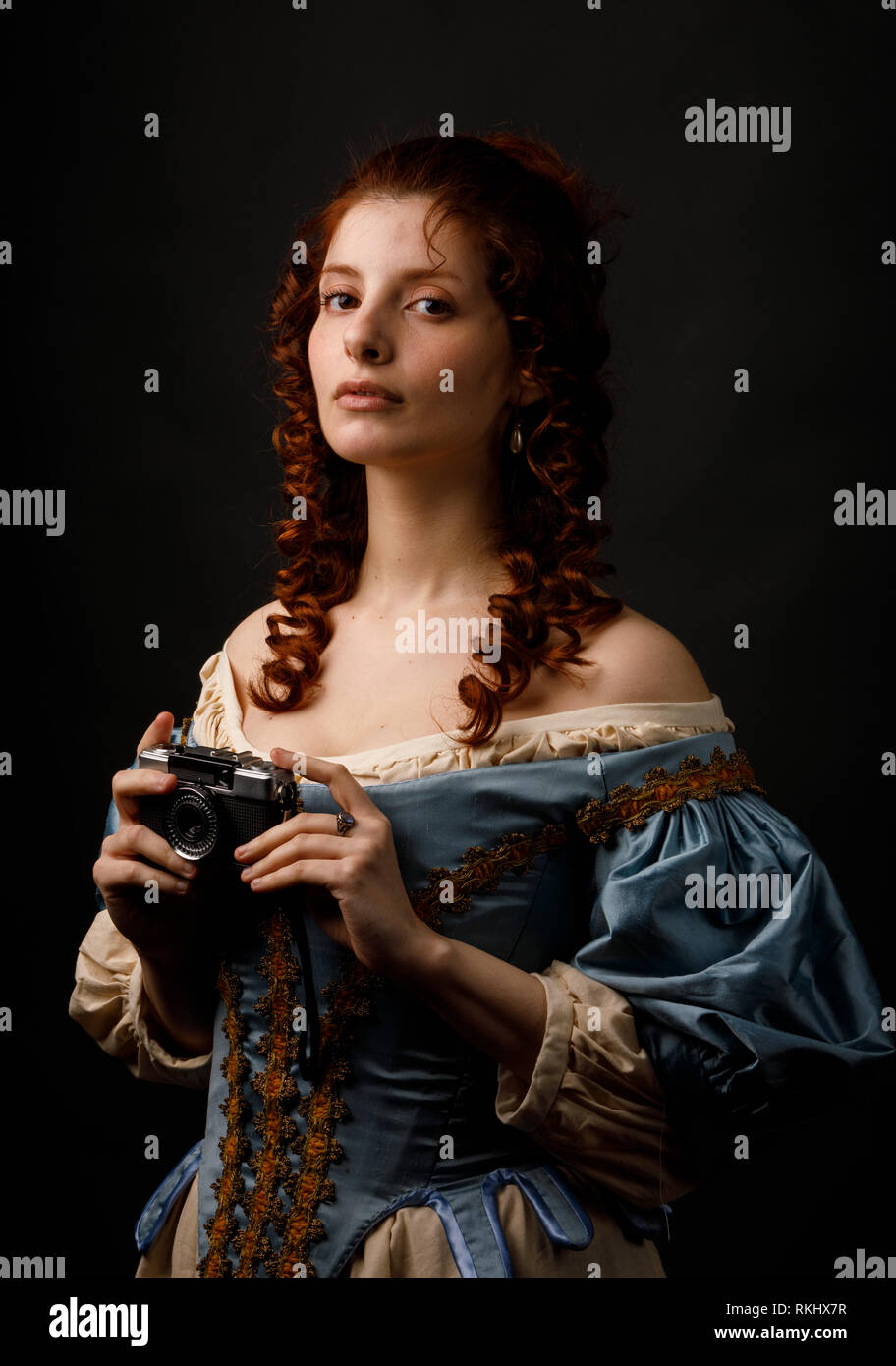 Schöne Frauen in hübschen barocken Kleid holding Foto Kamera und Kamera beim Stehen auf schwarzem Hintergrund Stockfoto
