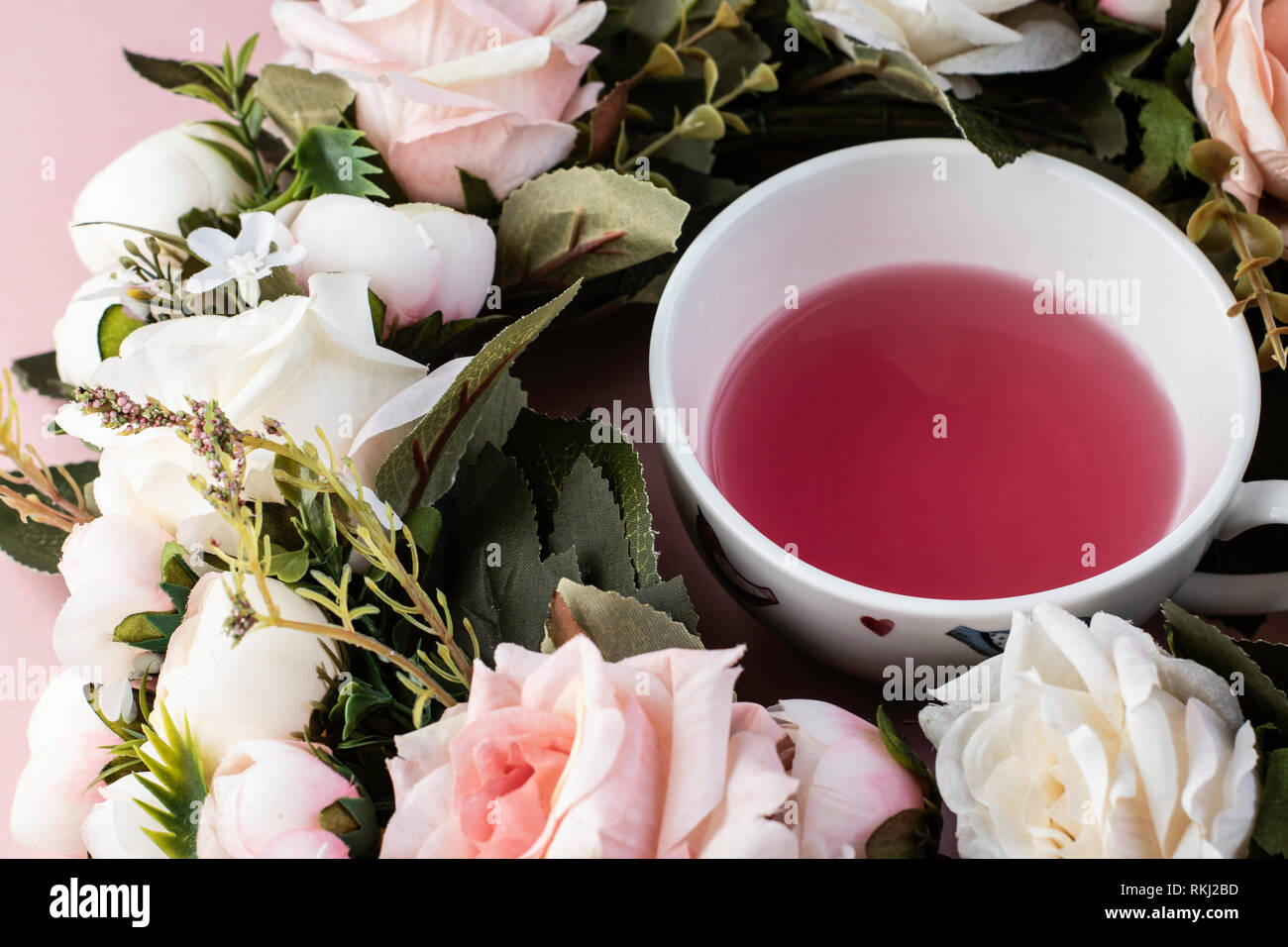 Teetasse in einem rosa und weiße Rose Wreath auf einem rosa Hintergrund Stockfoto
