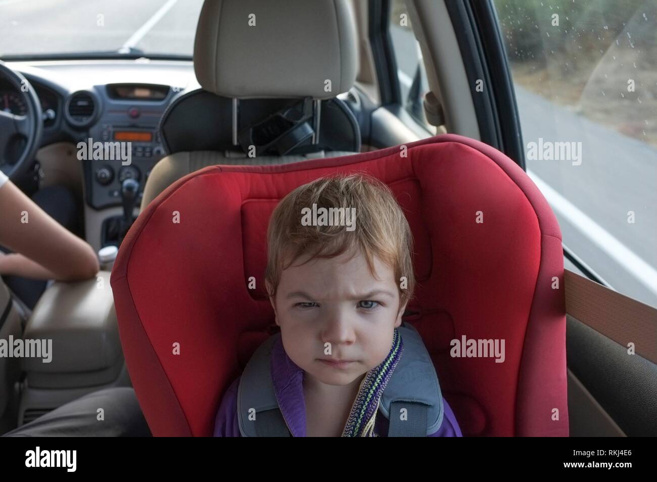 Schöne baby boy wird wütend auf Autositz. Überlebende eine lange Autofahrt mit Kindern Konzept. Stockfoto