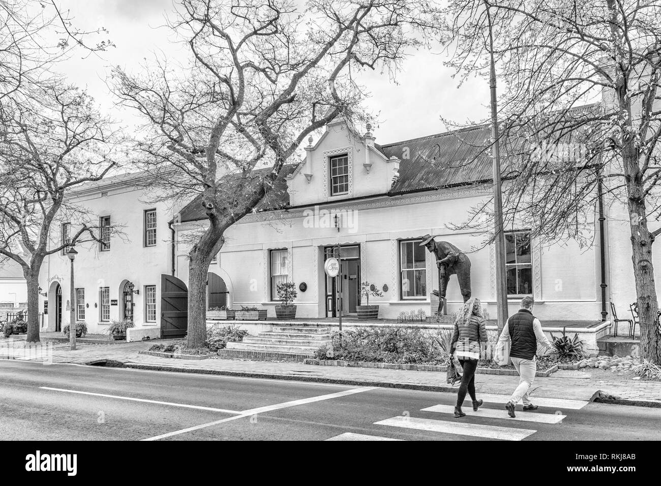 Stellenbosch, Südafrika, 16. AUGUST 2018: Historische Gebäude in Dorp Street in Stellenbosch in der Western Cape Provinz. Ein bergmann Statue und Menschen Stockfoto