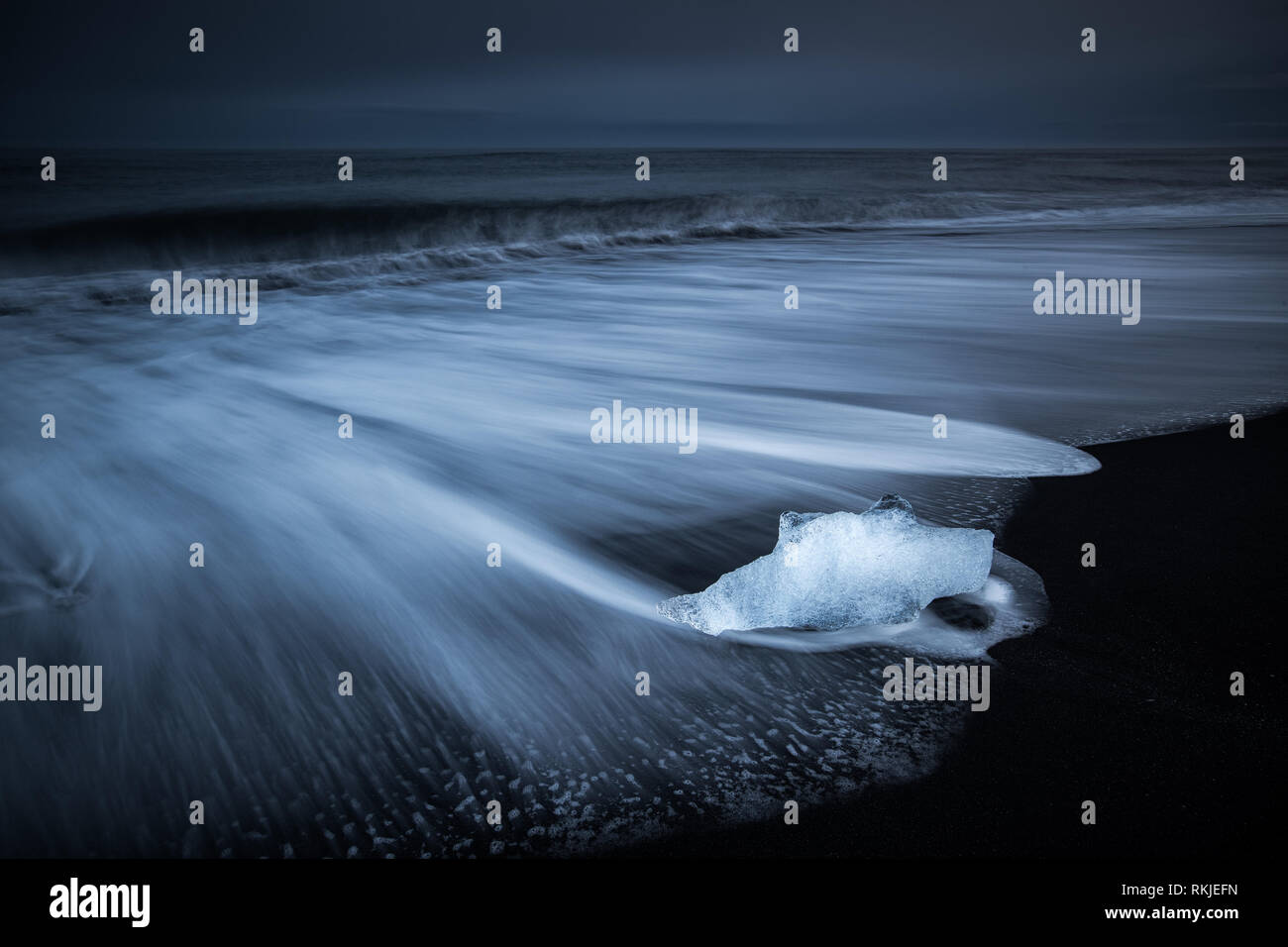 Meer driftet in um die Eisberge und das Gletschereis, die am Strand auf dem schwarzen Sand am Gletschersee Jökulsárlón, Island gefegt wird Stockfoto