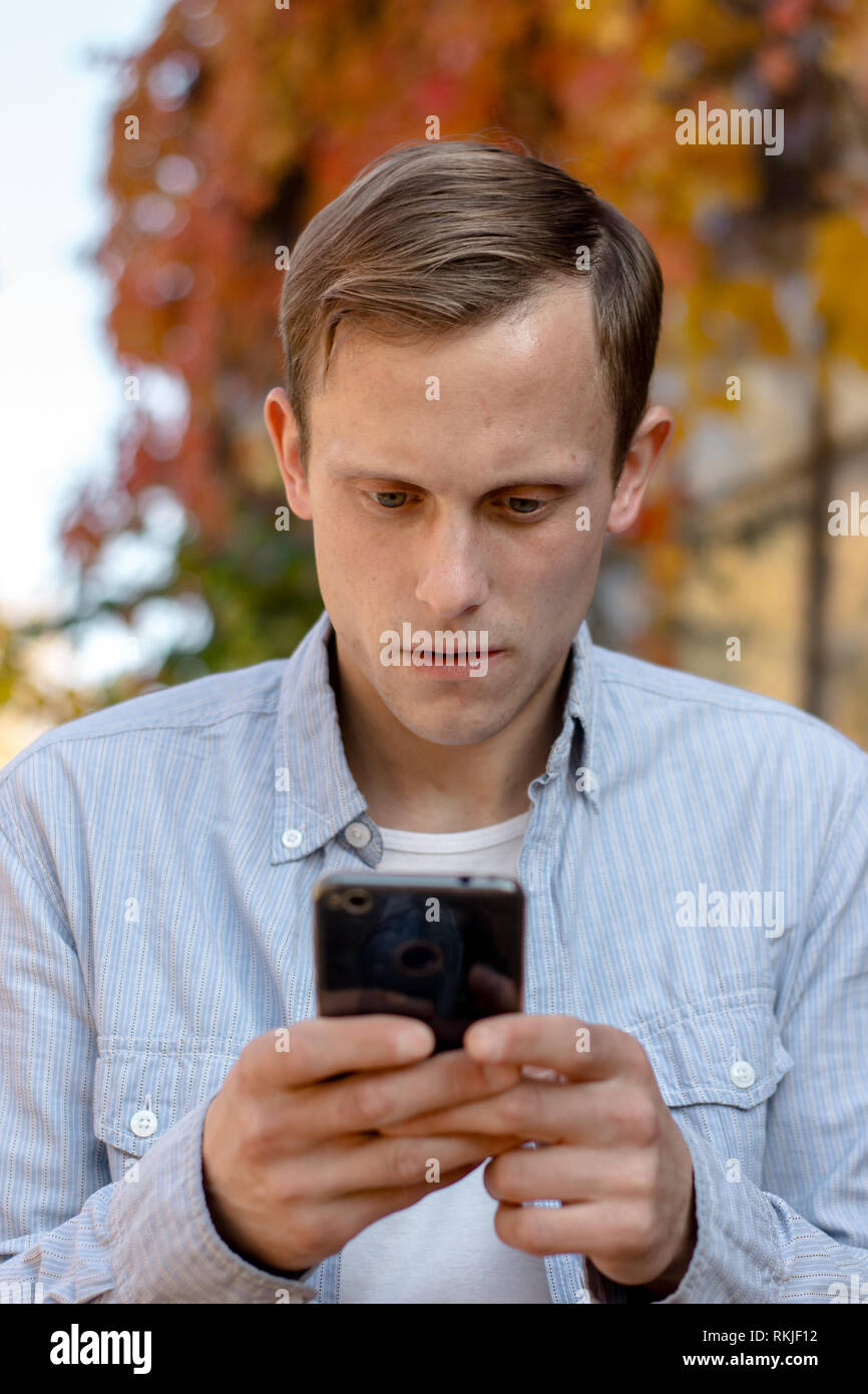 Portrait von Kerl mit einem Telefon in legere Kleidung im Herbst Park Stockfoto