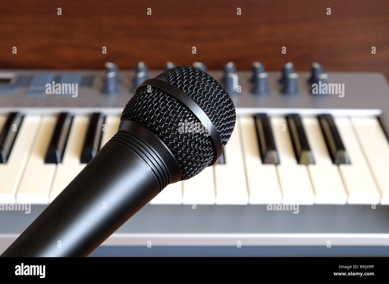 Schwarz Mikrofon schließen sich gegen elektronische Synthesizer Keyboard mit vielen Reglern in Silber Kunststoff Körper als Hintergrund Stockfoto