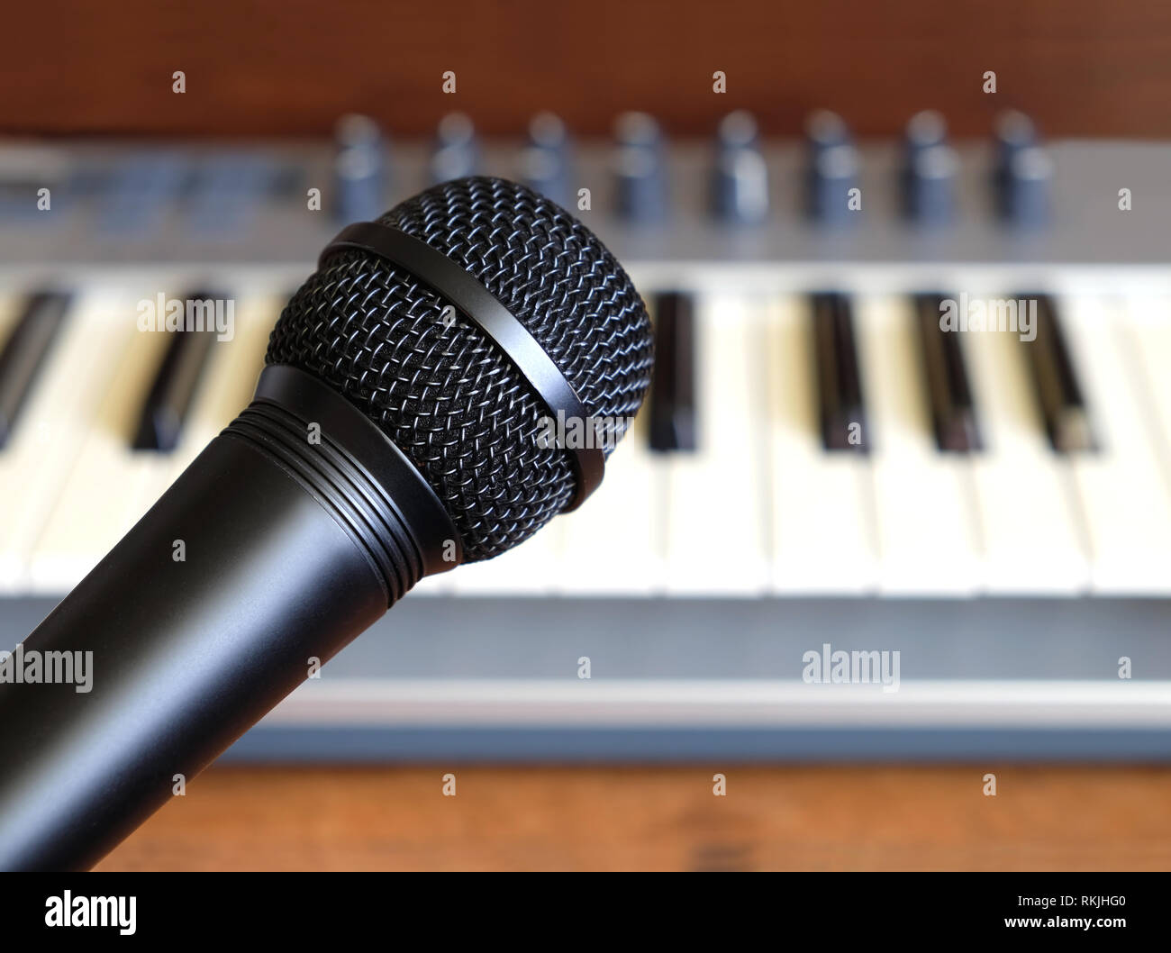 Schwarz Mikrofon schließen sich gegen elektronische Synthesizer Keyboard mit vielen Reglern in Silber Kunststoff Körper als Hintergrund Stockfoto