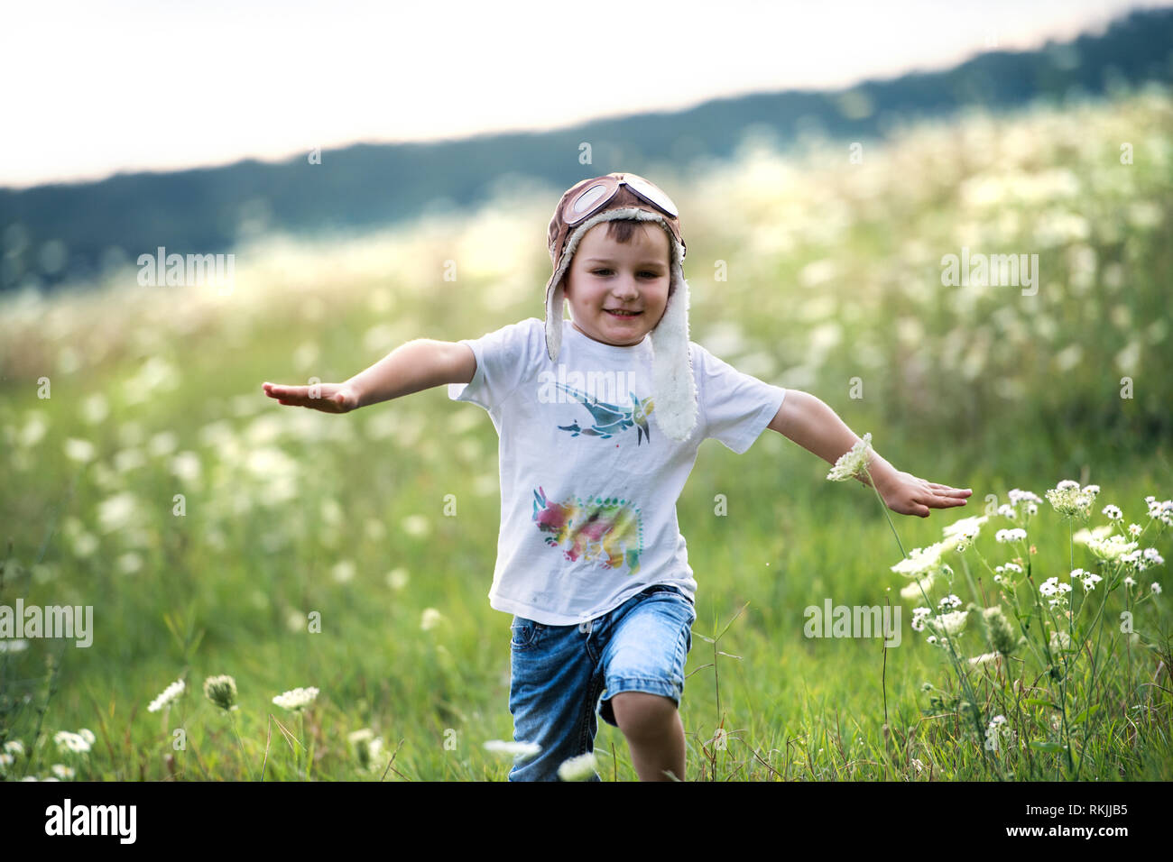 Ein kleiner Junge mit Pilot hat läuft in der Natur an einem Sommertag. Stockfoto