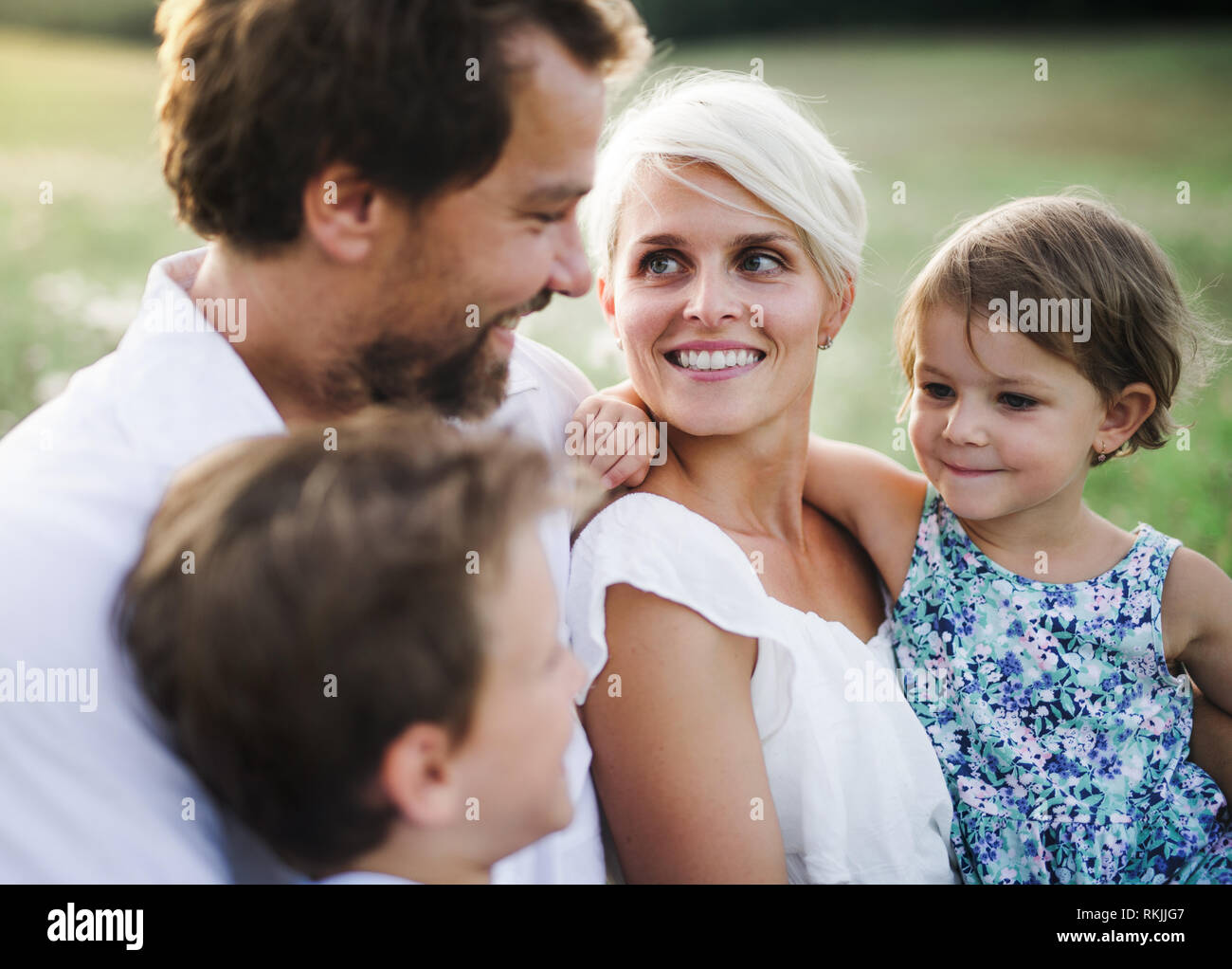Junge Familie mit kleinen Kindern im Sommer Natur bei Sonnenuntergang. Stockfoto