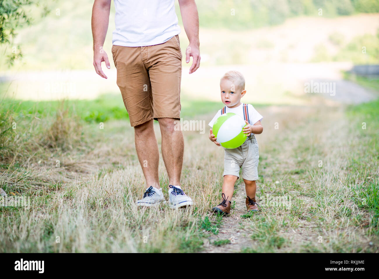 Junger Vater mit einem kleinen Kind Sohn wandern im sonnigen Sommer Natur. Stockfoto