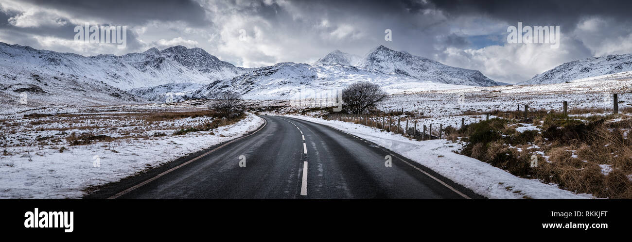 Eine Straße in verschneiten Snowdonia Nationalpark Berge führen im WInter Stockfoto