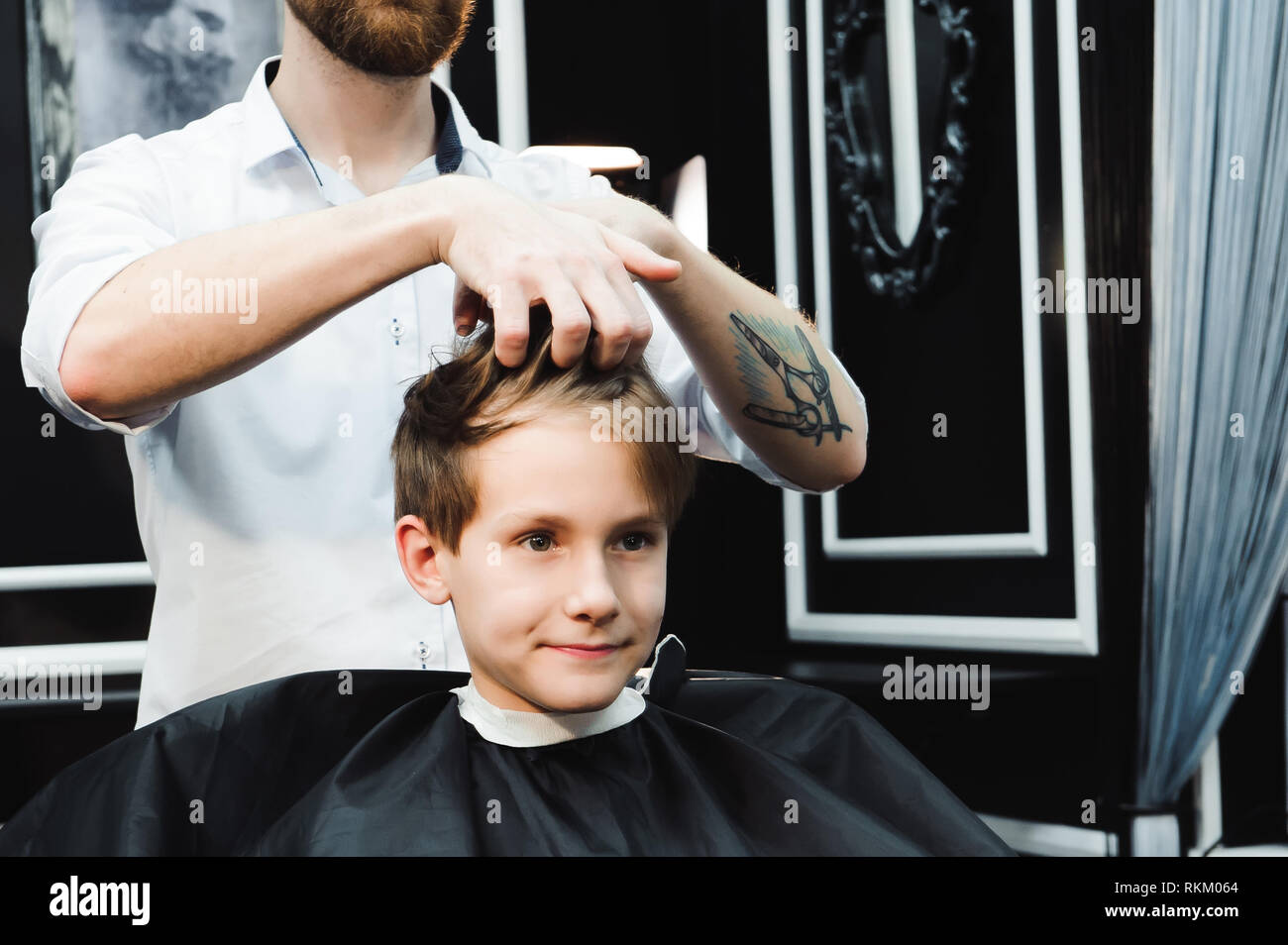 Junge schöne Friseur die Haare des jungen im barbershop Stockfoto