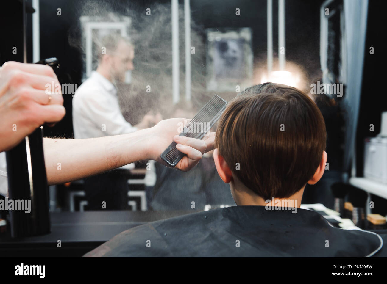 Junge schöne Friseur die Haare des jungen im barbershop Stockfoto