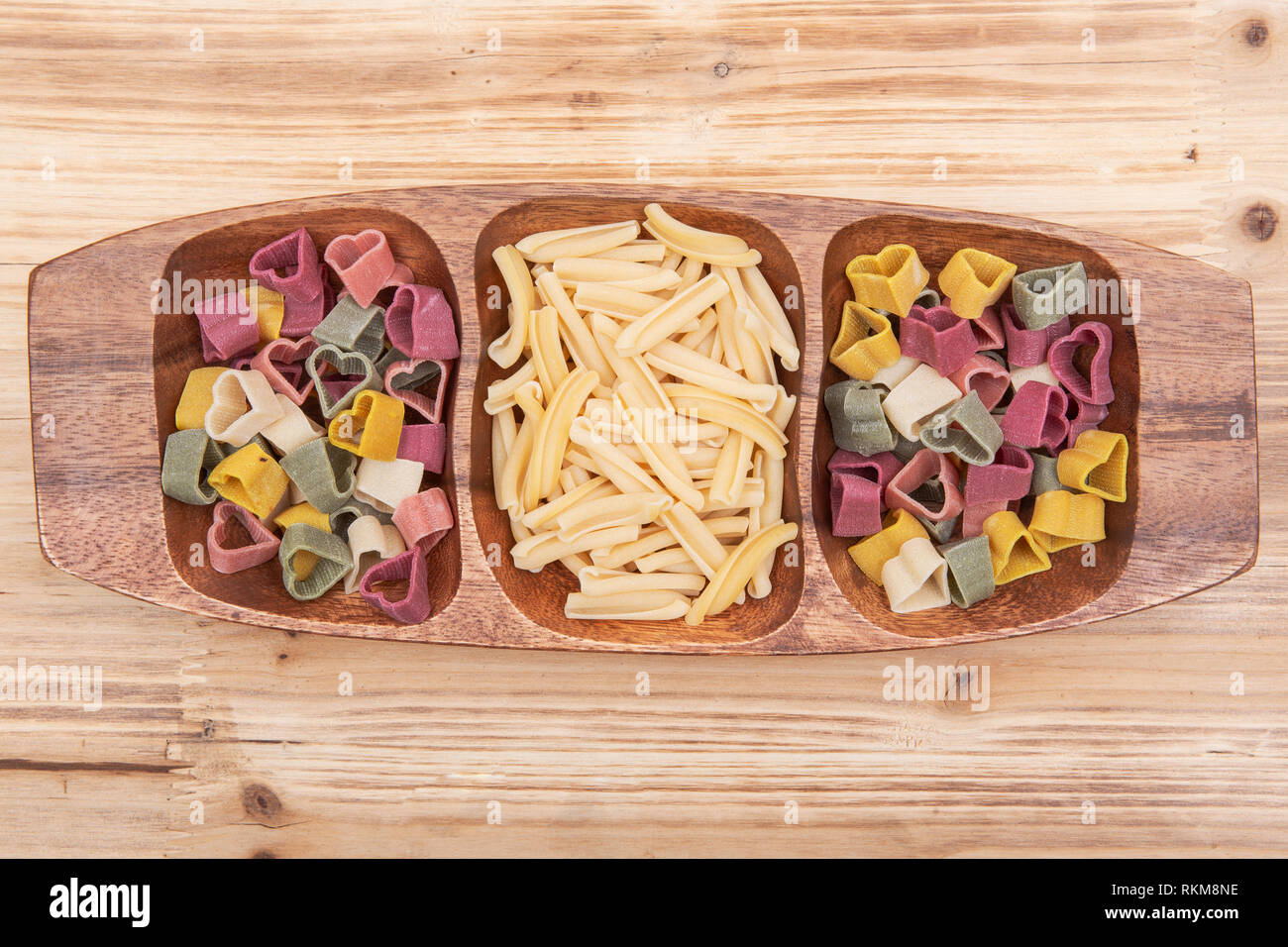 Ungekochte italienische Hartweizengrieß herzförmig und Casarecce Pasta auf eine lange Olivenholz Platte angeordnet sind. Stockfoto