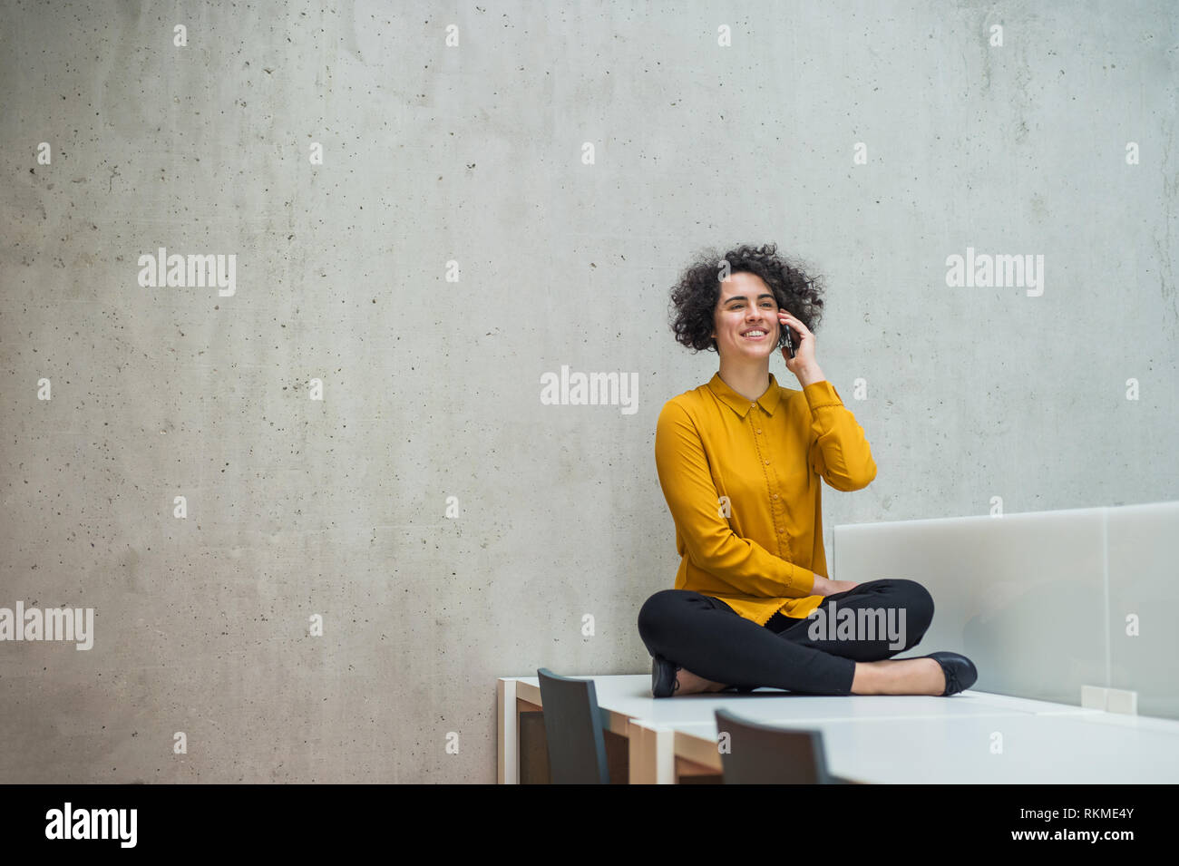 Junge student oder Geschäftsfrau, sitzen am Schreibtisch in einer Bibliothek oder einem Büro, mit Smartphone. Stockfoto