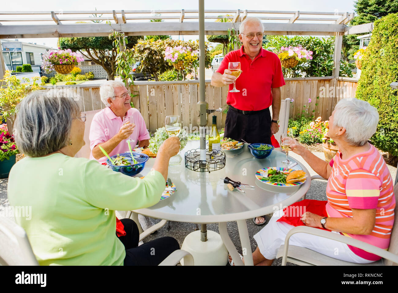 Zwei ältere Ehepaare genießen Sie eine Mahlzeit im Freien auf der Terrasse mit einem Glas Wein. Stockfoto
