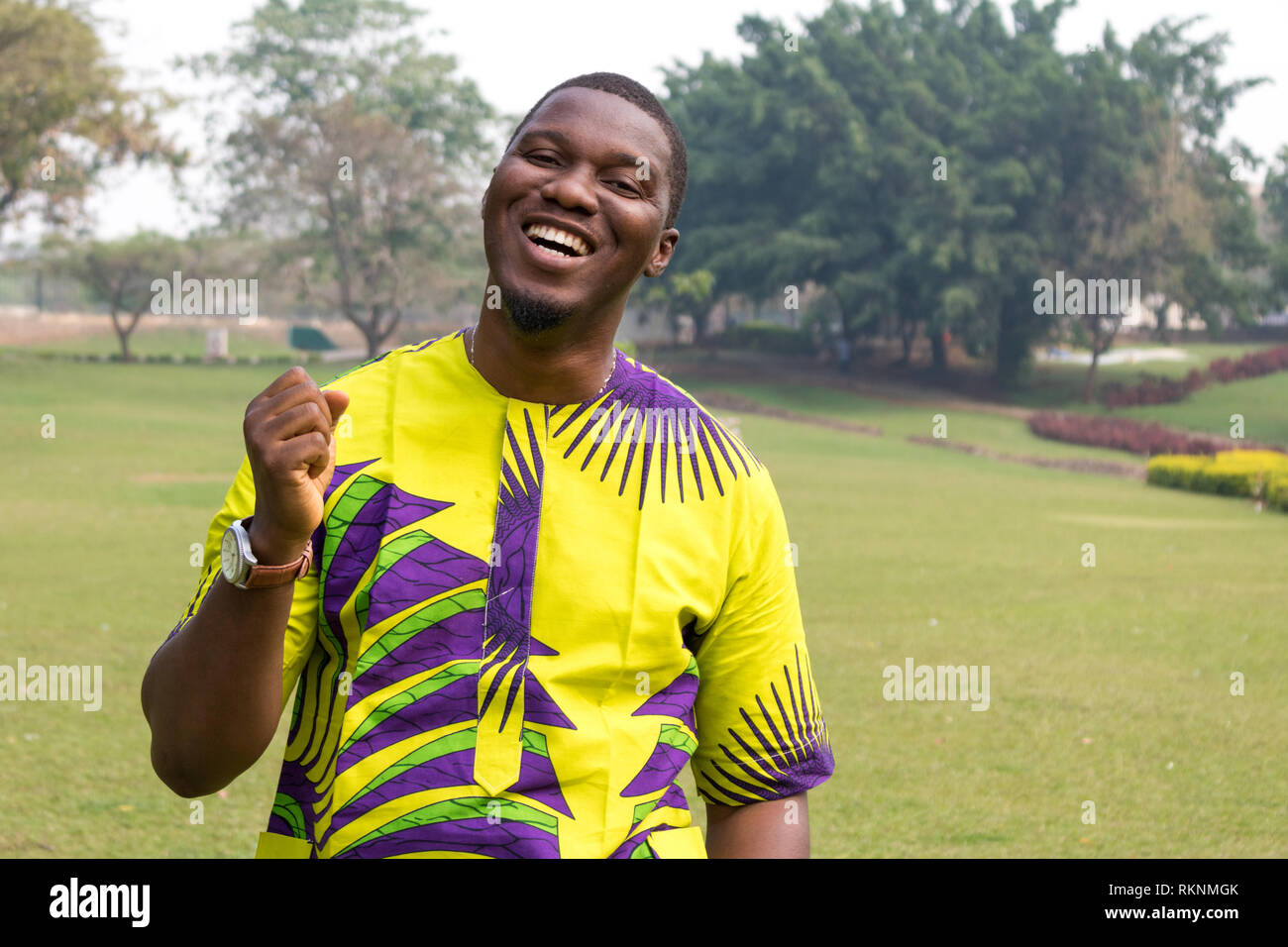 Ein afrikanischer Mann in ein offenes Feld des grünen Grases und klare Himmel öffnet sich die Hand in den Himmel, glücklich, Relief und lacht. Stockfoto