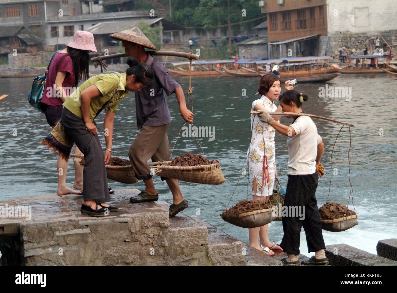 Die Arbeitnehmer Tragen von Lasten von Boden versuchen, jagt hinter Touristen in Fenghuang. Was bedeutet "Phoenix" auf Chinesisch, Fenghuang wurde nach der mythische Vogel o benannt Stockfoto