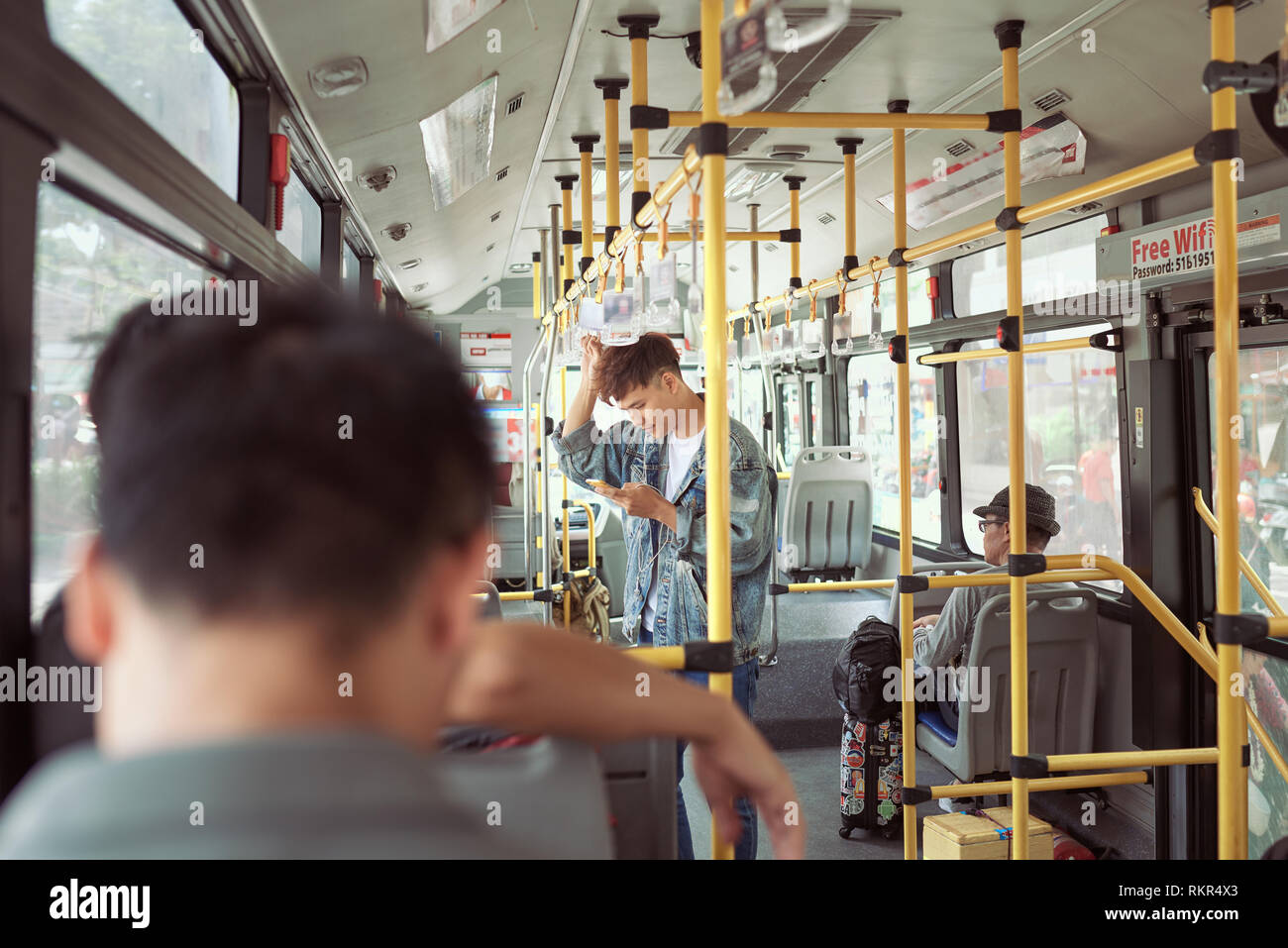 HO CHI MINH CITY, VIETNAM - 22 Juli, 2017: hübscher junger Mann in eine blaue Jeansjacke mit Smartphones im Bus Stockfoto