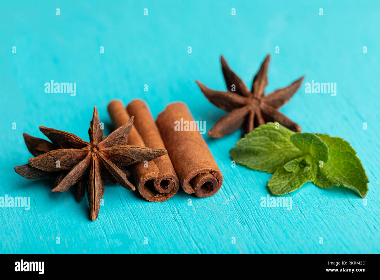 Sticks von Zimt mit mint Sprig und Anis Sterne auf Türkisfarbenem Hintergrund. Stockfoto