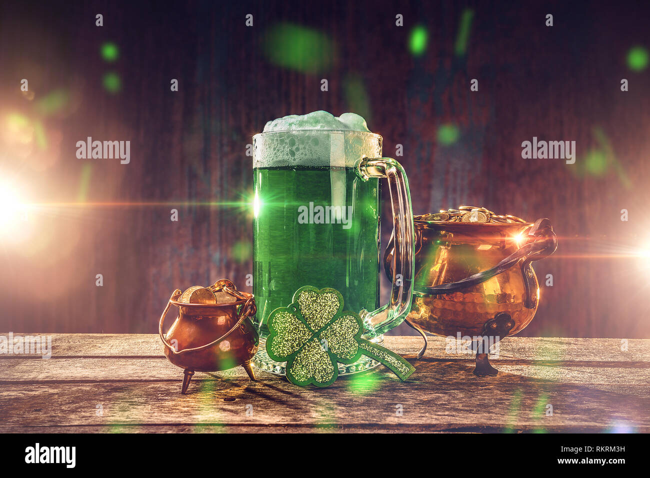 Hintergrund für den St. Patrick's Day mit einem Glas grün Bier, Goldmünzen und ein Shamrock auf einem Holztisch. Stockfoto