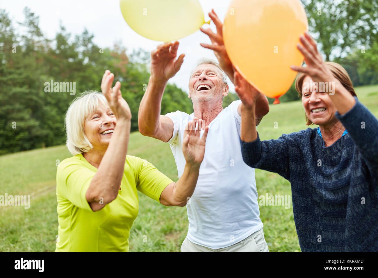 Happy Senioren spielen mit Ballons zu einem Sommerfest im Park Stockfoto
