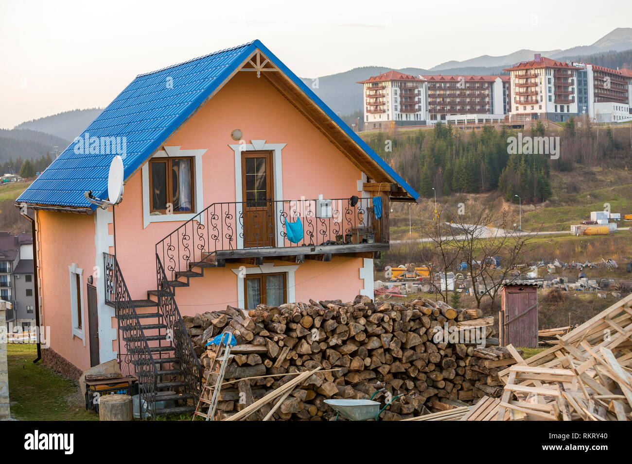 Zweistöckiges Wohn- Ferienhaus Haus mit Schindeldach, verputzte Wände, geschmiedete Balkon und Außentreppe, Haufen von Brennholz in ökologischen Mo Stockfoto