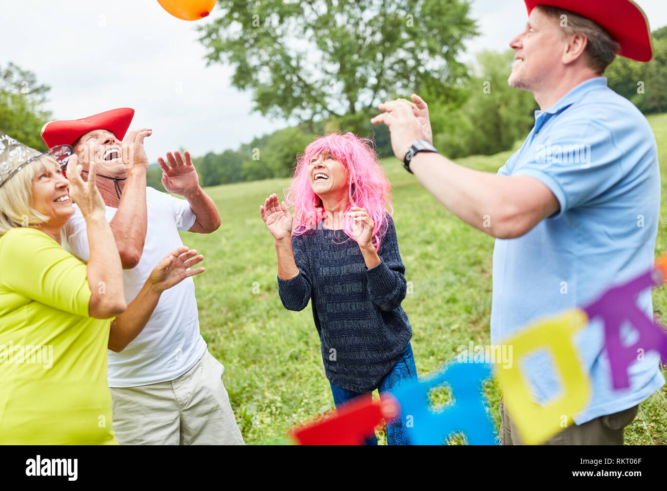 Feiern Gruppe von Senioren und in bunten Kostümen auf einer Geburtstagsparty spielen Stockfoto